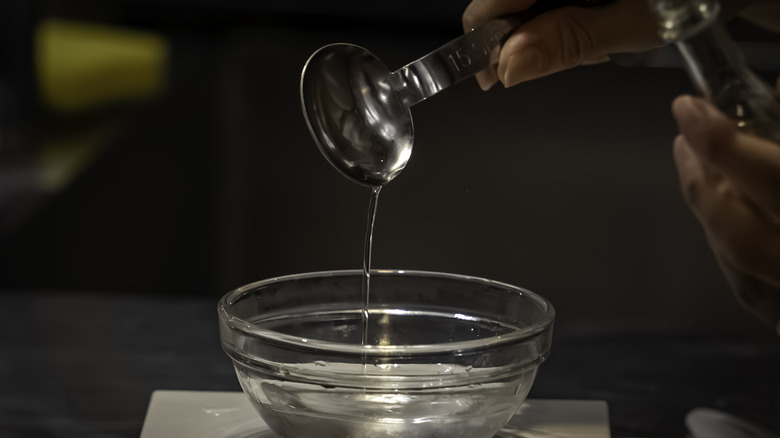 pouring a tablespoon of water into clear ramekin