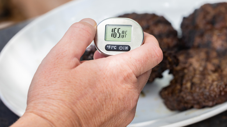 person using digital meat thermometer on steak