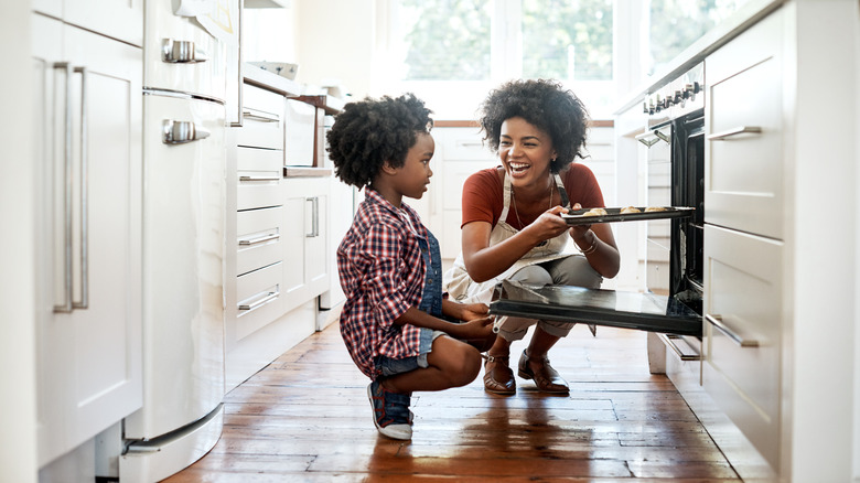 woman and child take cookies out of oven