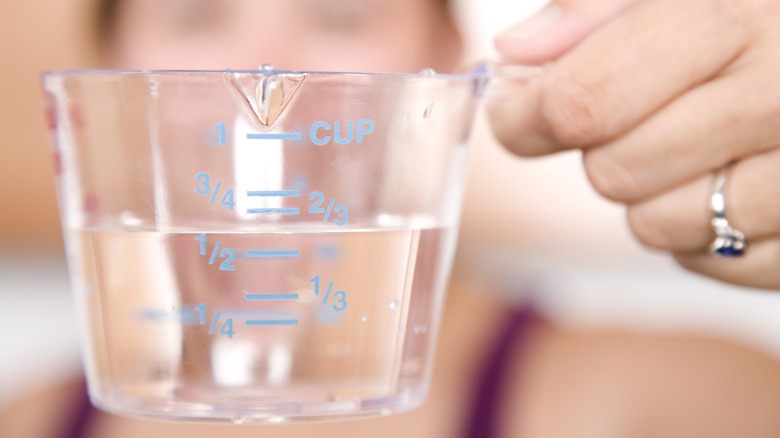 woman holding measuring cup of water