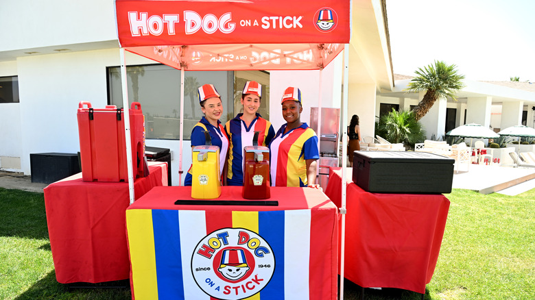 Three employees manning a Hot Dog on a Stick stand