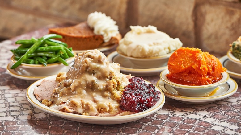 Thanksgiving-style dishes including turkey, gravy. green beans, and mashed potatoes on tiled table