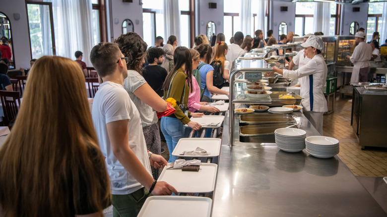 People line up with trays at cafeteria restaurant