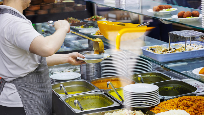Server pouring soup into bowl at cafe lineup