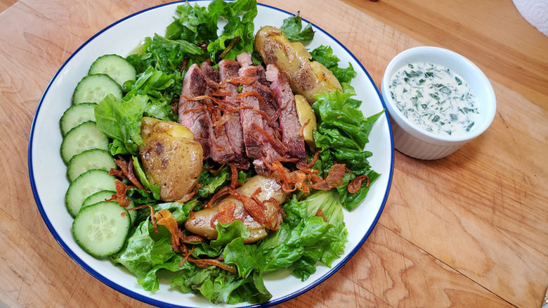 A Pittsburgh salad on a plate with a side of ranch sauce