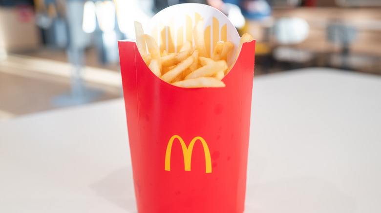 A  full McDonald's fry containter positioned upright on a table.