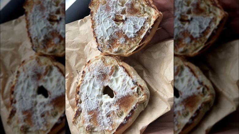 Two toasted bagel halves covered in cream cheese.