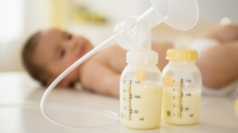 breast milk bottles and pump with baby in background