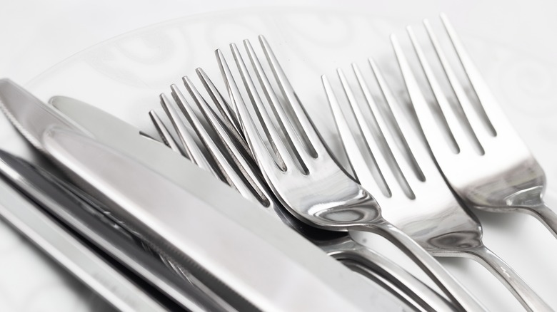 silver knives and forks stacked side by side