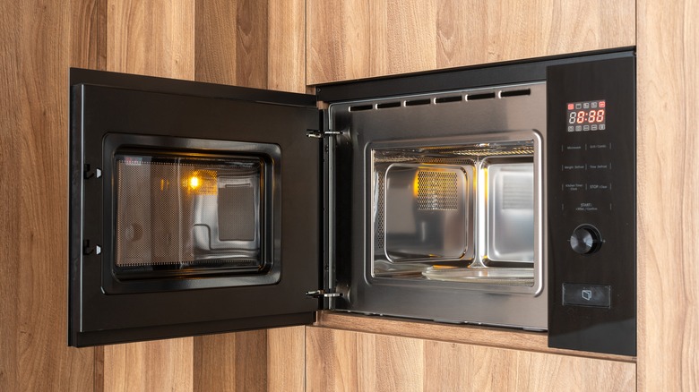 empty black microwave built into wooden wall