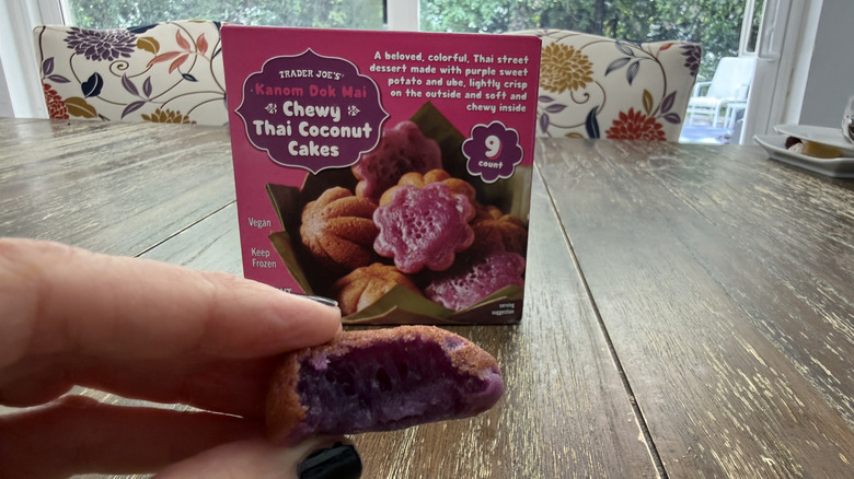 Trader Joe's Chewy Thai coconut cakes package on a wooden table and a hand holding one