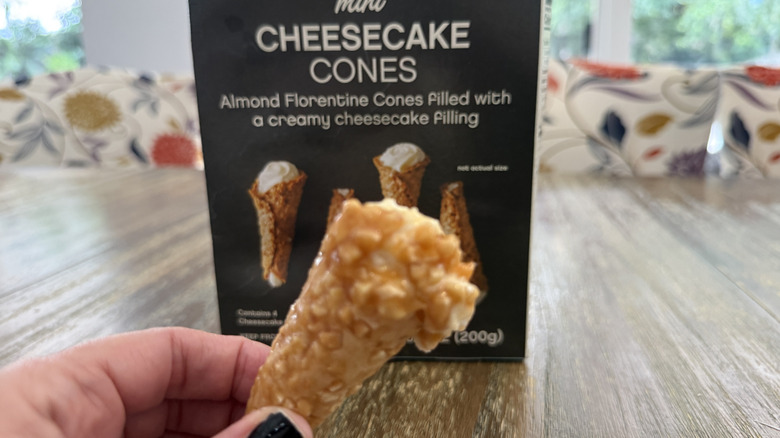 Trader Joe's mini cheesecake cones package on wooden table and a hand holding one