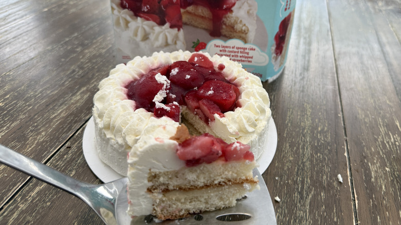 Trader Joe's Strawberries and Cream Cloud Cake on wooden table with a slice scooped out of it