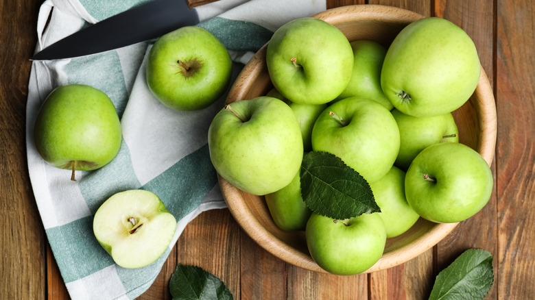 Granny Smith apples in bowl on wood table