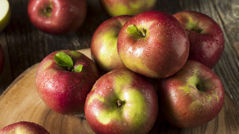 McIntosh apples stacked on a wooden board and table