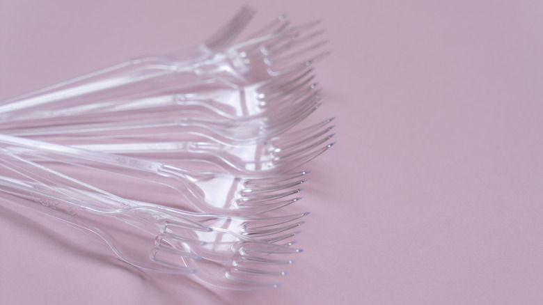 Several plastic forks on a light pink background