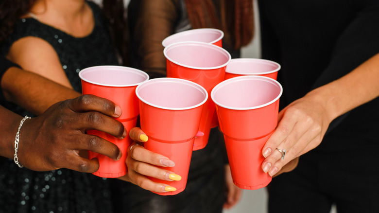 Several hands cheering with red plastic cups