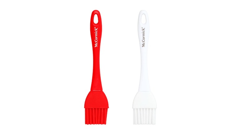 Two silicone basting brushes beside one another, one red and one white, on a white background.