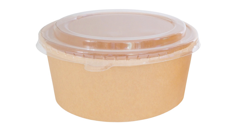 A round cardboard to-go container with a clear plastic lid