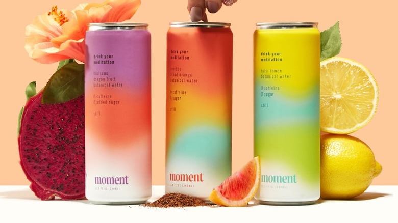 hand pulling the tab on one of three Moment cans