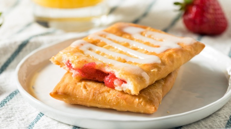 A plate with two strawberry filled toaster pastries with icing