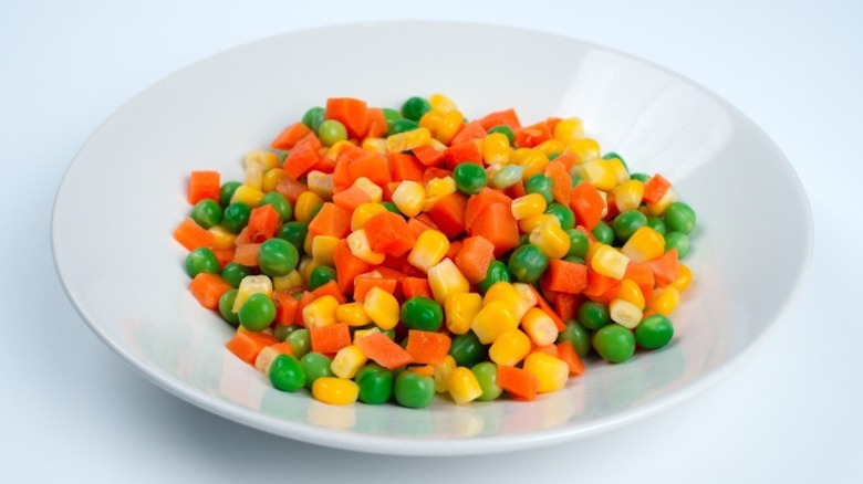 A bowl of mixed vegetables (corn, peas, carrots) on a white background