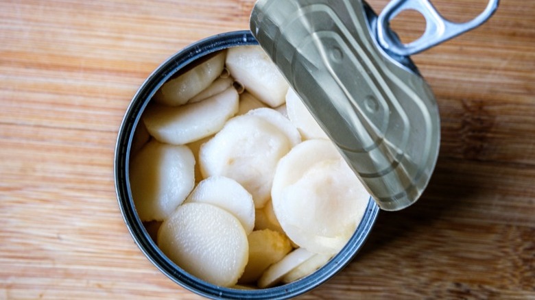 An open can of water chestnuts on a wooden surface
