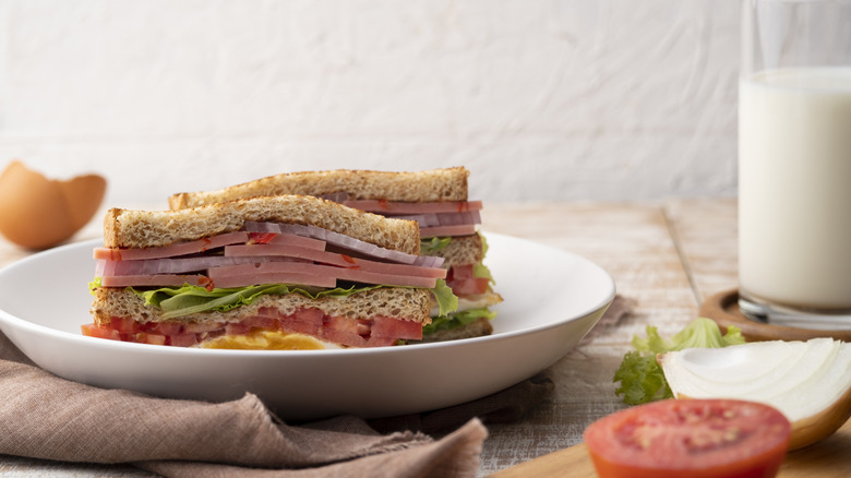 Tall bologna sandwich cut in half on plate