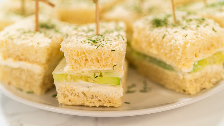 Cucumber sandwiches cut into finger sandwiches on plate with toothpicks