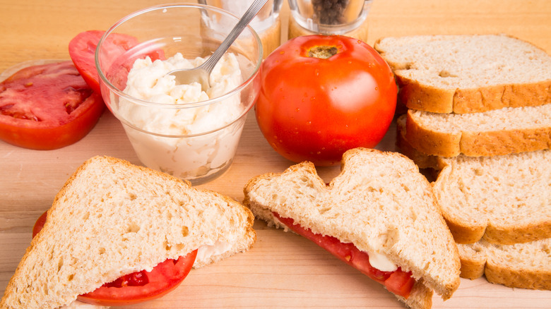 Tomato, bread, and mayonnaise on cutting board for a tomato sandwich