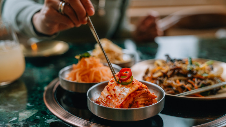 Hand with chopsticks grabbing fermented vegetables
