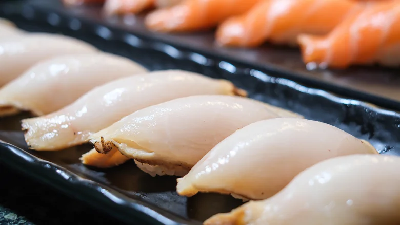 Escolar nigiri lined up on black serving plate
