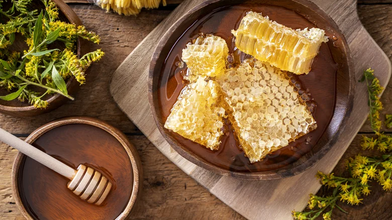 Raw honeycomb and honey on wooden table