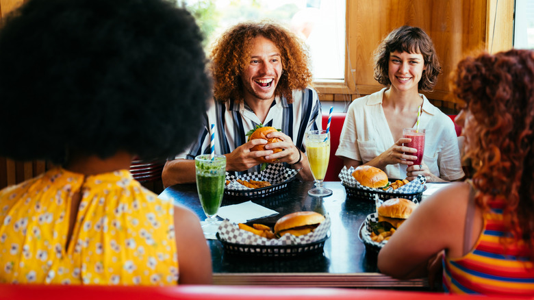 Group of diners enjoy burgers and conversation at restaurant
