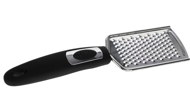 A Dollar Tree Cooking Concepts cheese grater with rubber handle on a white background