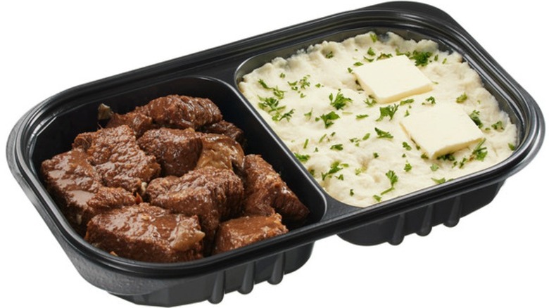 Kirkland Signature Braised Beef with Yukon Mashed Potatoes in a two-sided black plastic container on a white background.