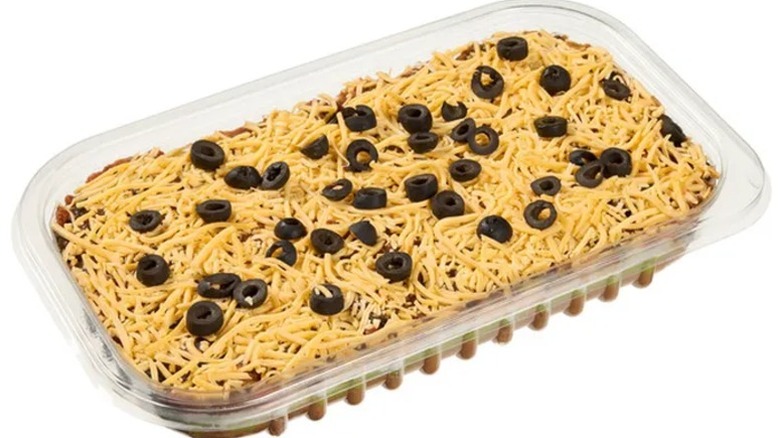 A clear plastic container of Costco Six-Layer Dip on a white background.