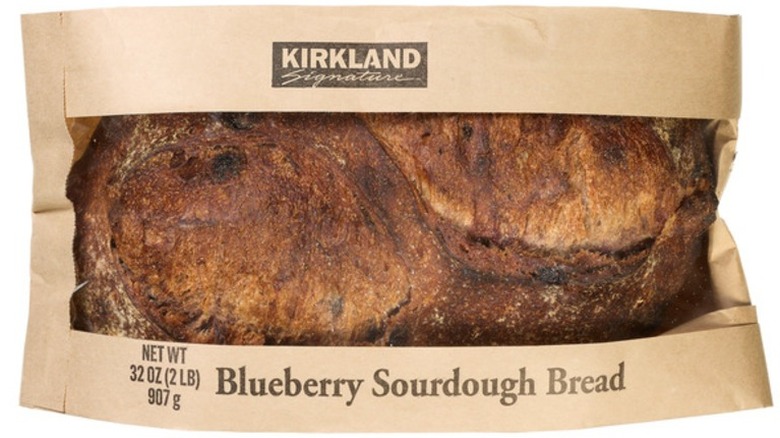A brown paper-wrapped loaf of Kirkland Signature Blueberry Sourdough Bread on a white background.