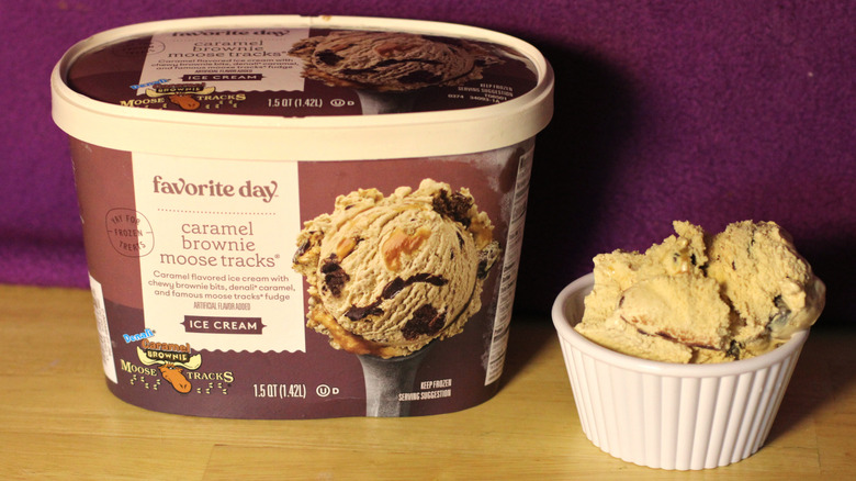 A container of Target's Favorite Day brand caramel brownie moose tracks flavored ice cream beside a bowl of the scooped ice cream