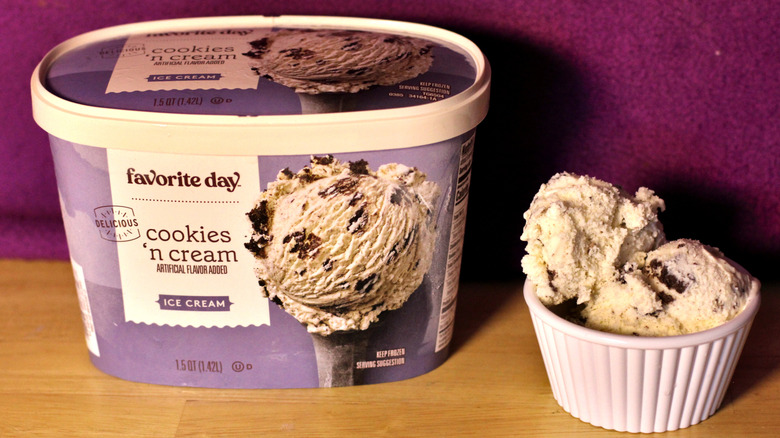 A container of Target's Favorite Day brand cookies and cream flavored ice cream beside a bowl of the scooped ice cream