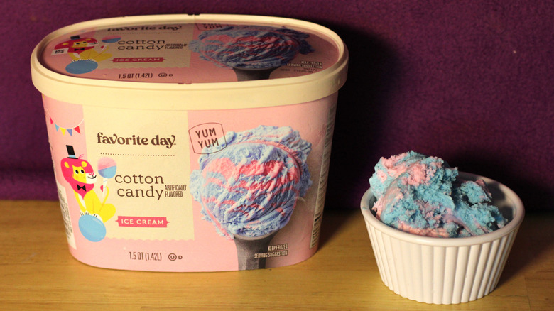 A container of Target's Favorite Day brand cotton candy flavored ice cream beside a bowl of the scooped ice cream