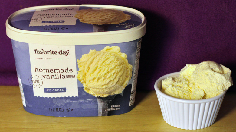 A container of Target's Favorite Day brand homemade vanilla flavored ice cream beside a bowl of the scooped ice cream