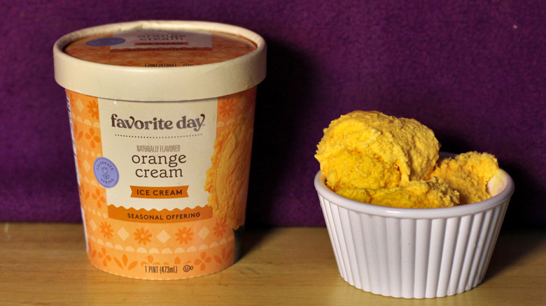 A container of Target's Favorite Day brand orange cream flavored ice cream beside a bowl of the scooped ice cream