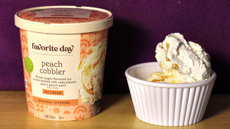 A container of Target's Favorite Day brand peach cobbler flavored ice cream beside a bowl of the scooped ice cream
