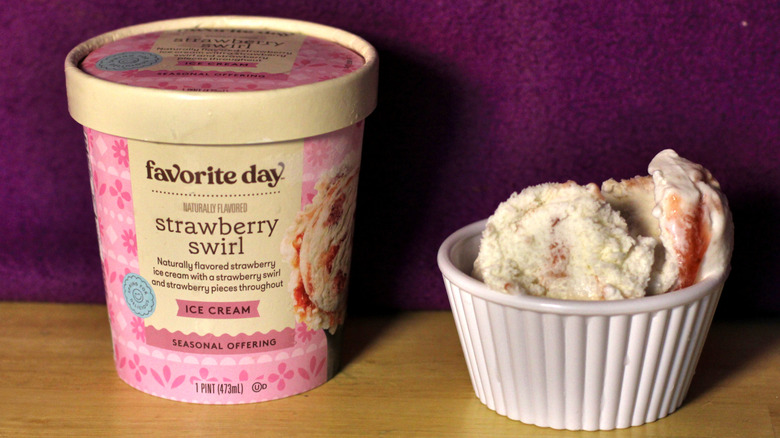 A container of Target's Favorite Day brand strawberry swirl flavored ice cream beside a bowl of the scooped ice cream