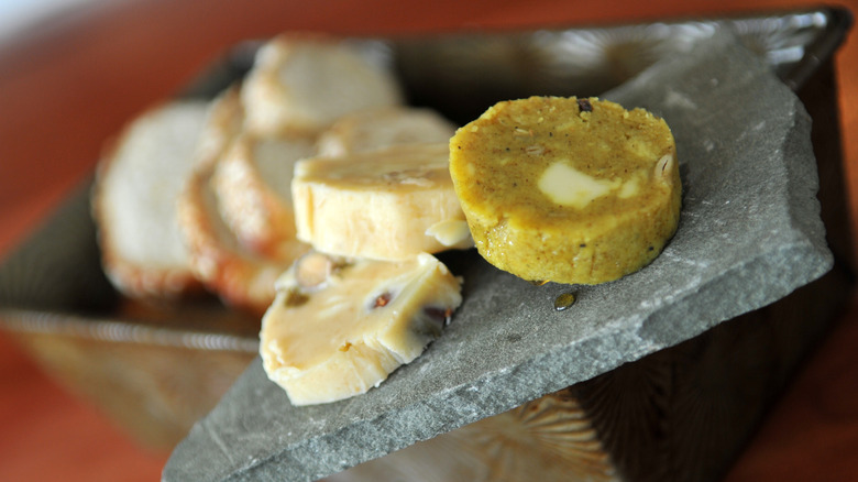 Slices of various compound butters on a slate slab