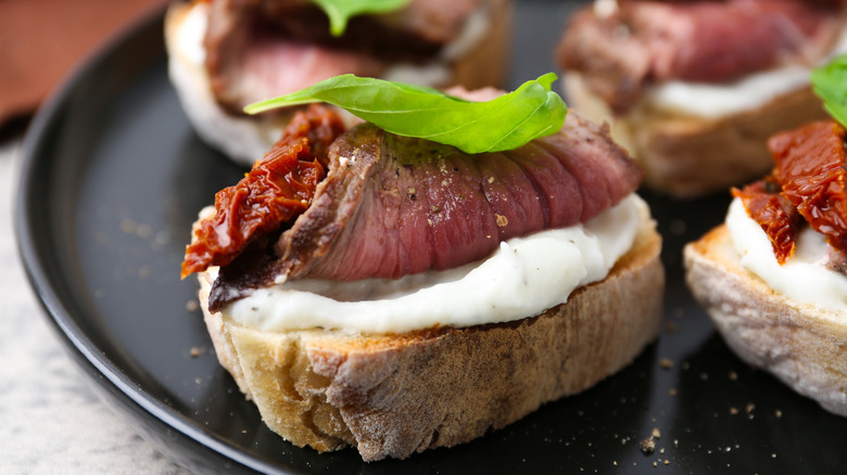 A close-up of a platter of roast beef and cream cheese crostini