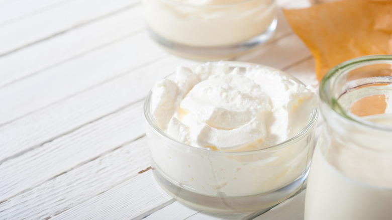 A glass ramekin of crème fraîche on a white table