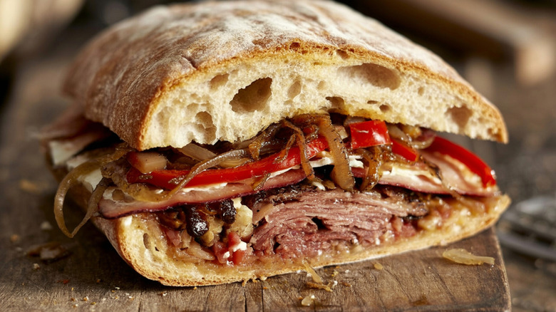 Close-up of a loaded roast beef sandwich on a wood surface