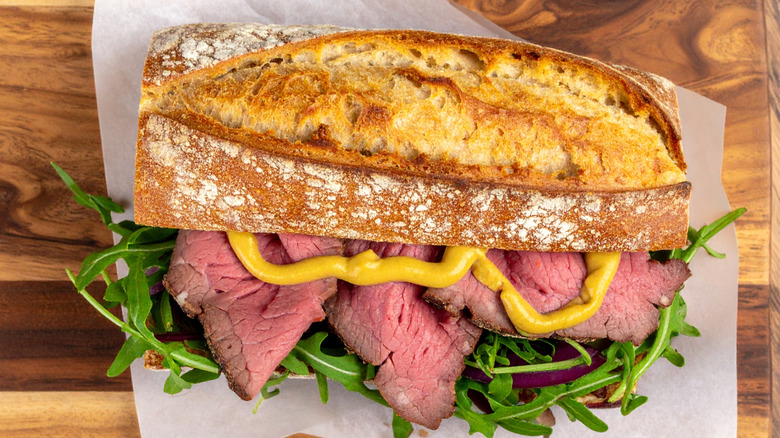 An overhead shot of a roast beef sandwich dressed with mustard